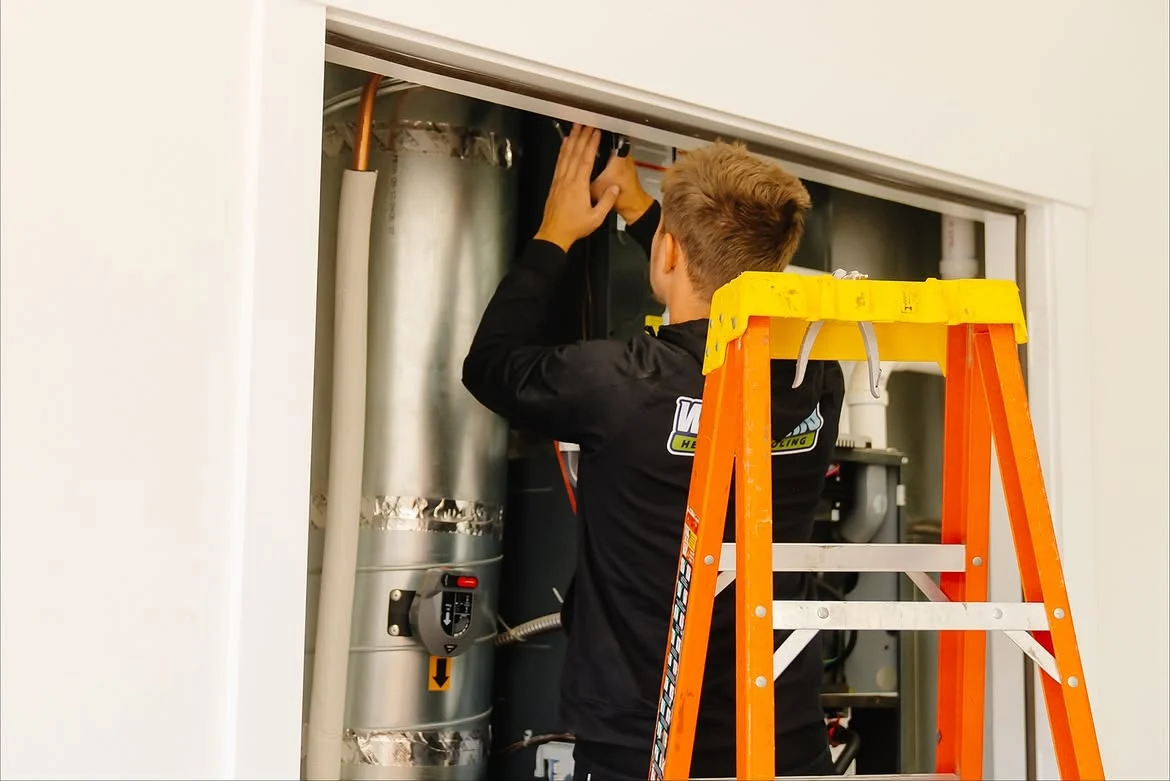 Technician connecting sheet metal ductwork above a furnace